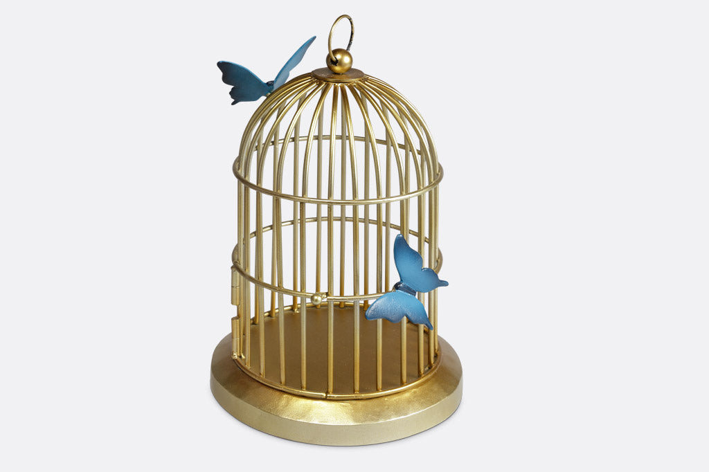 Butterflies of blue are sculpted onto a golden bird cage style plant or candle holder