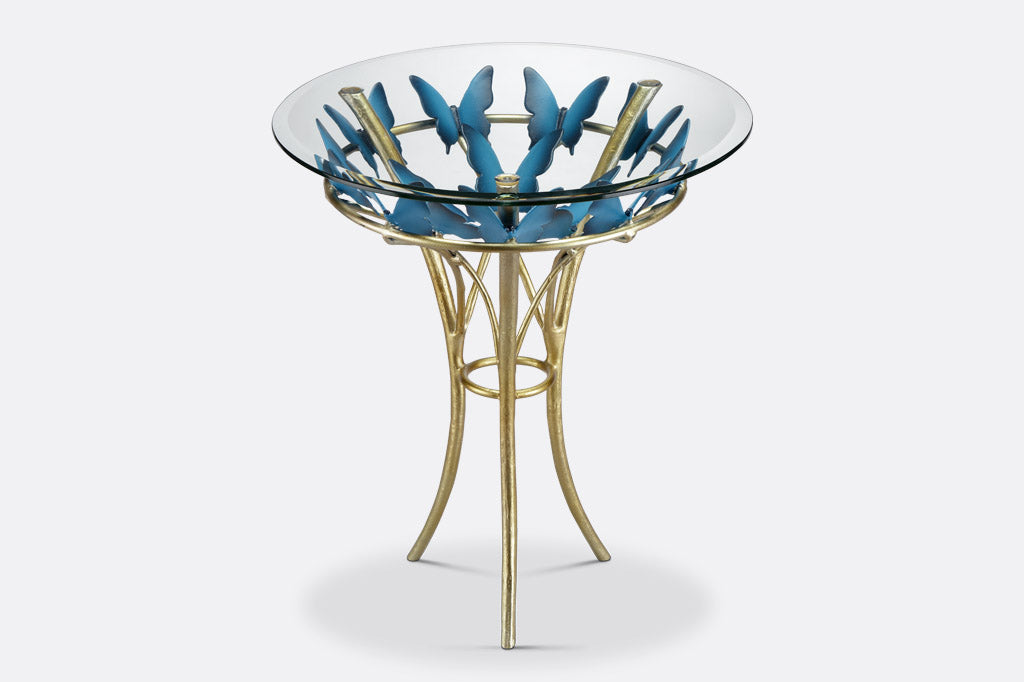 modern table with gold finish table supports and blue butterflies; glass top with beveled edge