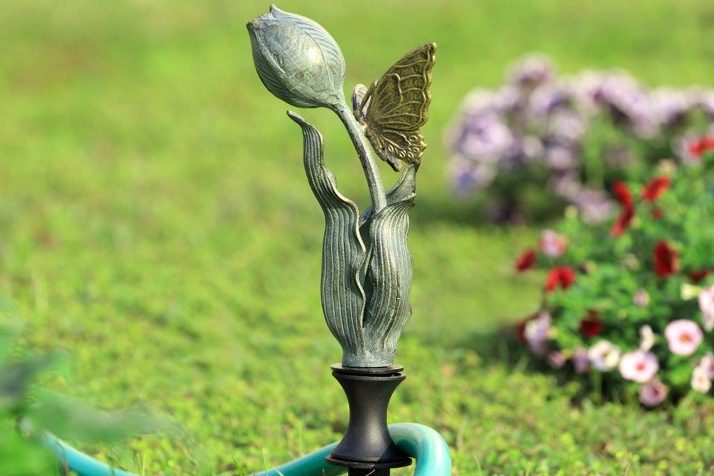 on lawn by bushes and hose, tulip shaped hose guard with golden butterfly