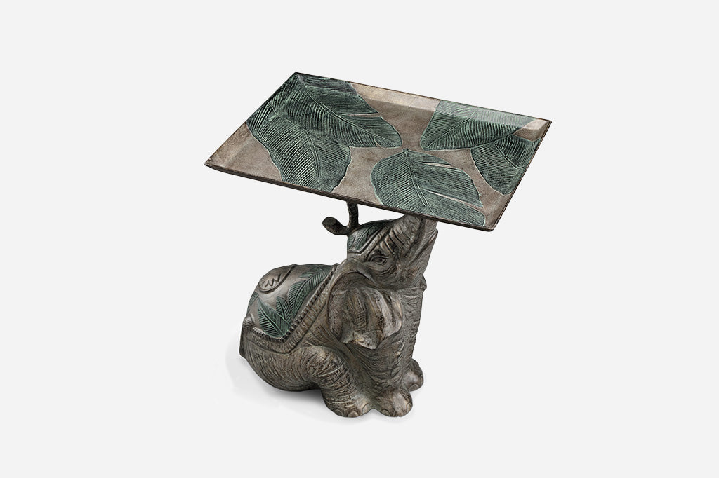 Indian elephant wearing palm motif blanket holds a tray embossed with palm branches