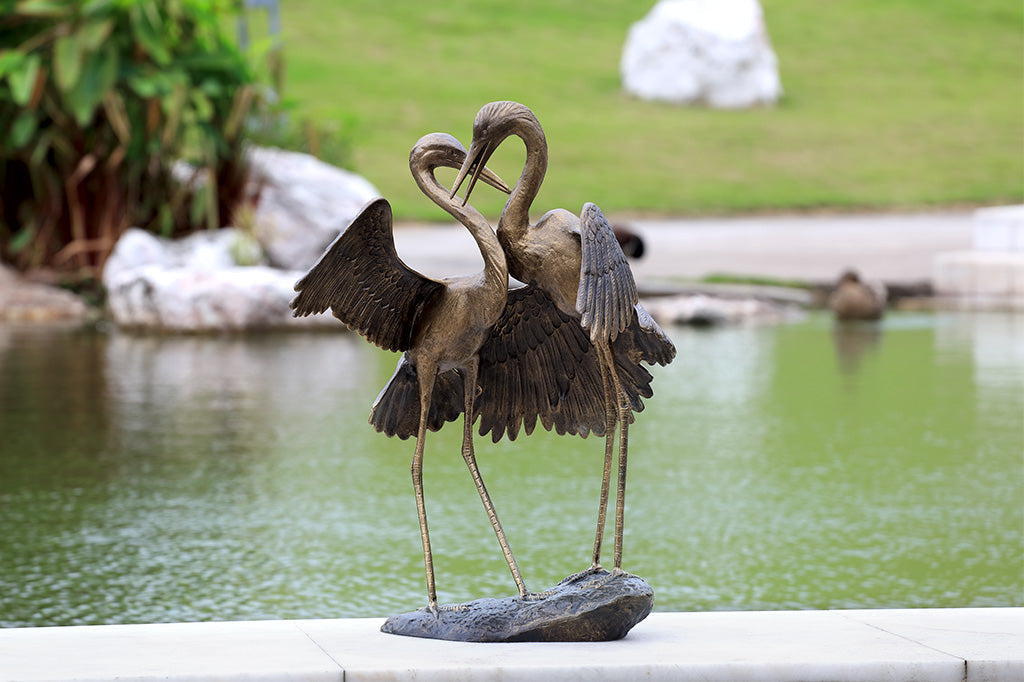 adoration crane sculpture - two cranes hugging with one wing placed in front of lake