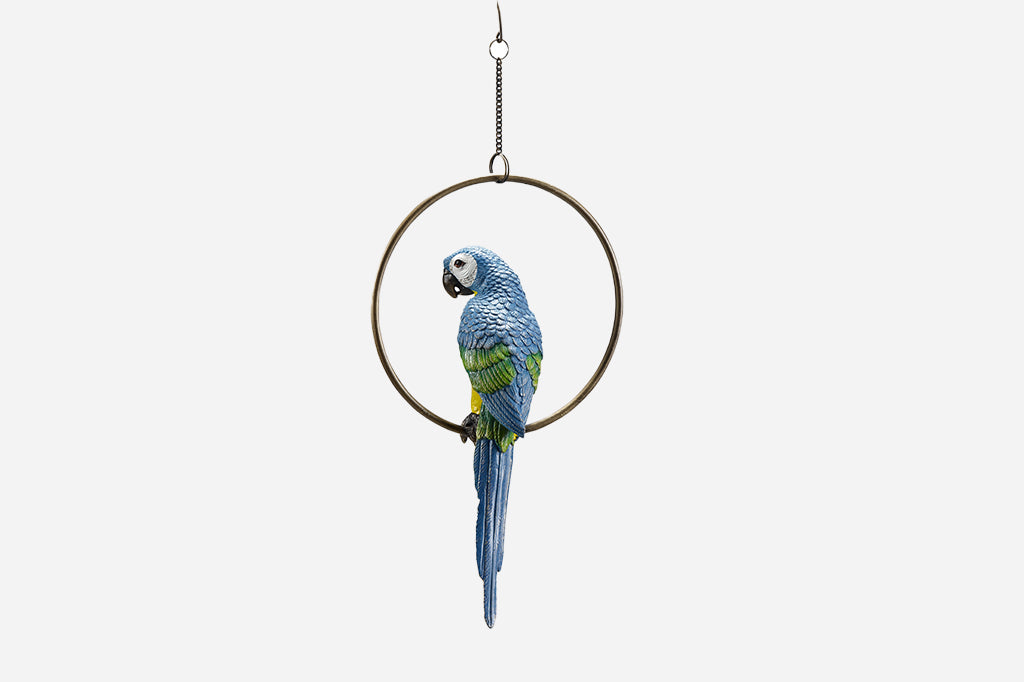 Yellow and blue parrot sculpture on hoop shown outside - view of backside blue and green feathers