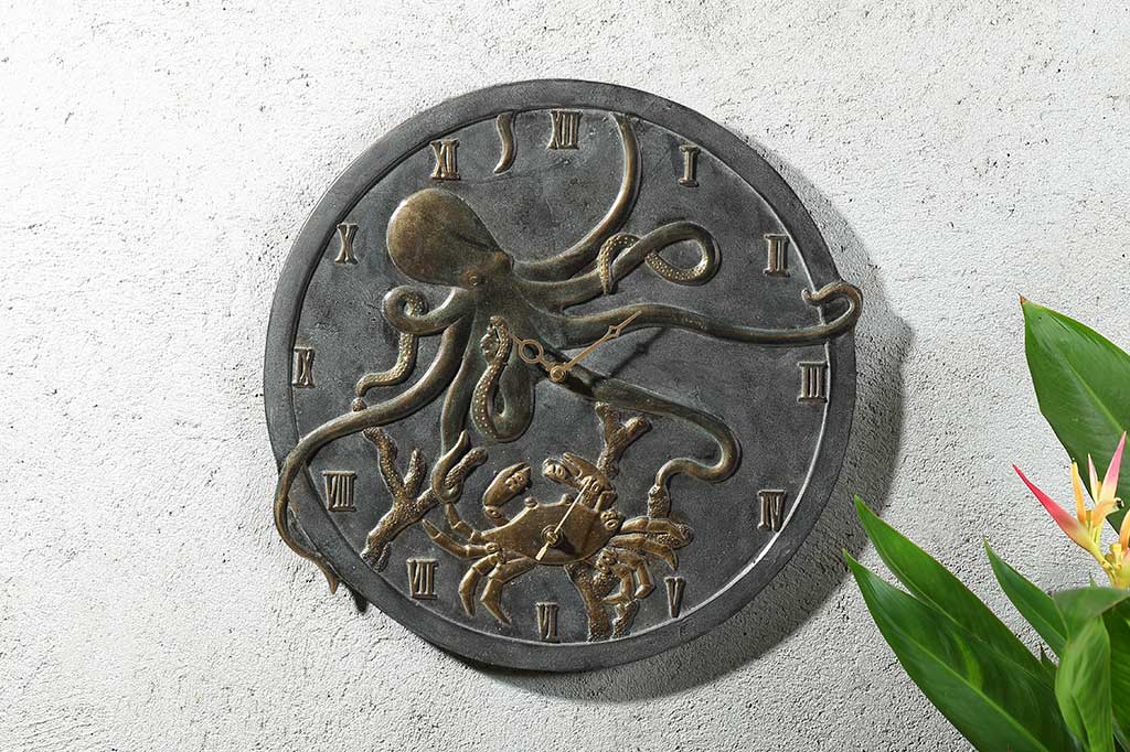 cast metal clock and thermometer with octopus with crab detailing. Set on outdoor wall with birds of paradise in corner