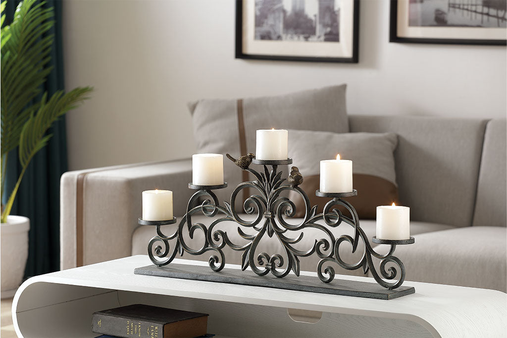 Uccelli e Alloro Pillar Candelabra with 5 pilar candles featured on a coffee table in a living room with couch and plant