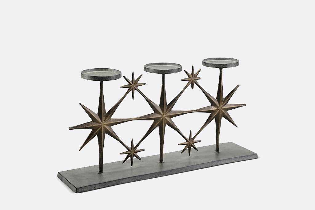 metal candleholder with large star motifs holding three candles side view