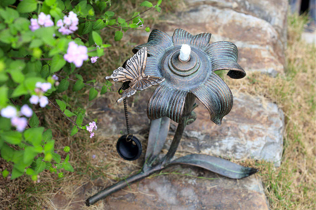 outdoor footed oil torch in sculpted lily and butterfly motif with accent snail - top view of butterfly detail