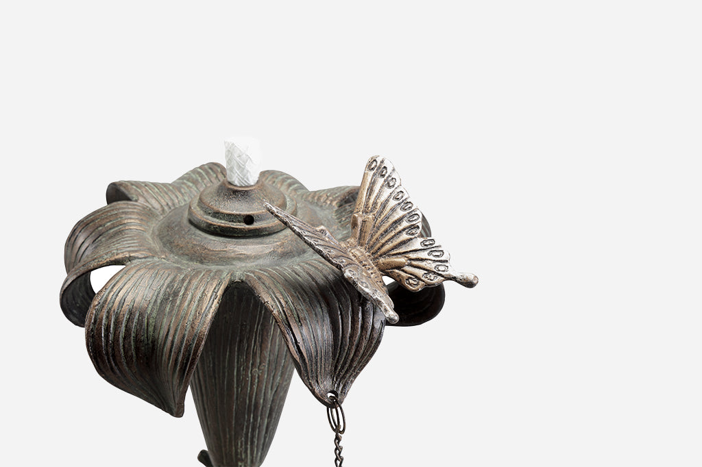 outdoor footed oil torch in sculpted lily and butterfly motif with accent snail