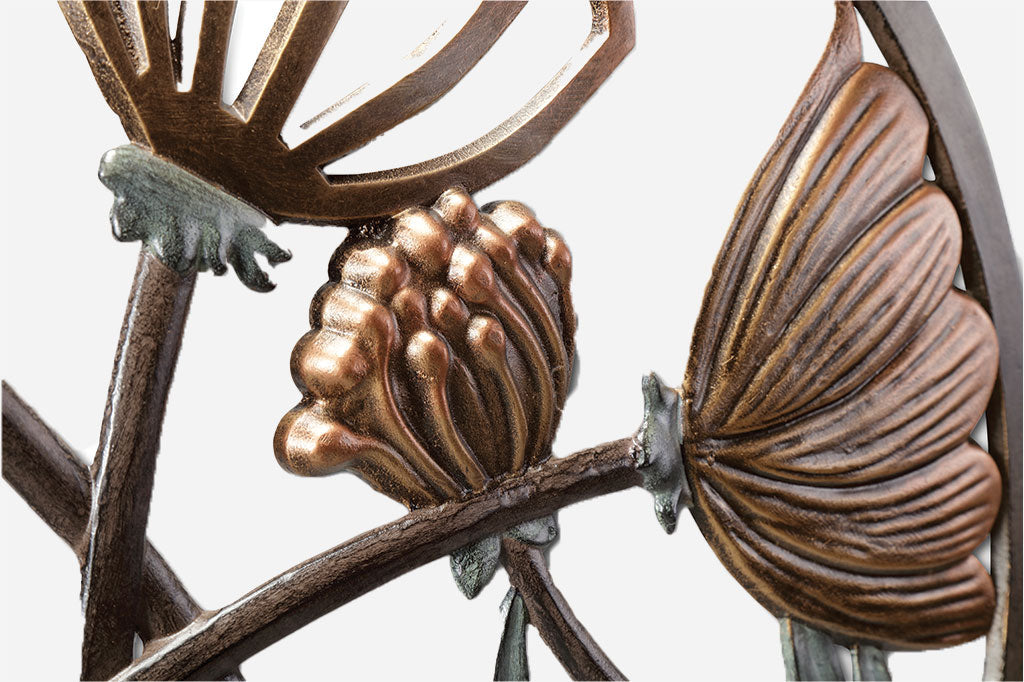 close up view of Cast metal rcular wall plaque of thistle and blossom