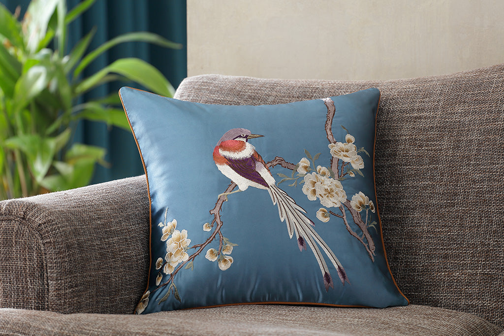 #color_blue
dark blue satin pillow with embroidered imagery of a bird perched on flowering branch placed on couch