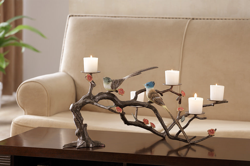 metal candelabra with branch and blossoms featuring two playful birds, holds up to 5 votive candles set on coffee table