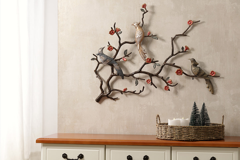 wall art of blossoming branches with three birds one light gold, one bronze and one with a metallic grey-blue tone 
