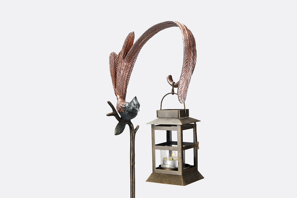 Close up of image in flycatcher bird in blue and soft pink holding lantern with tealight inside