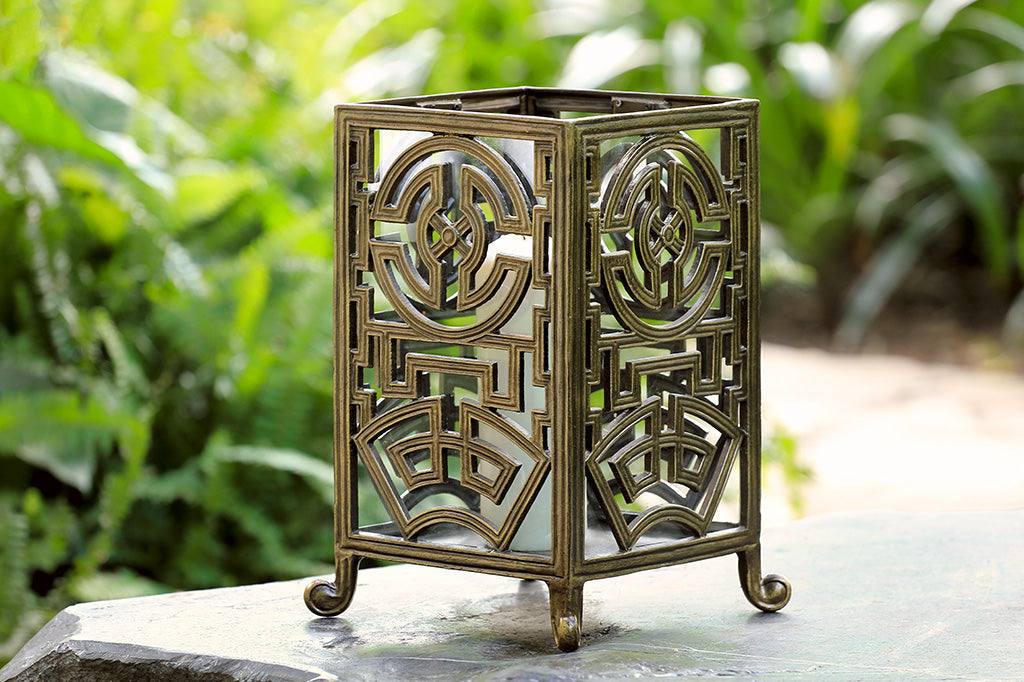 rectangle lantern with Asian inspired designs in a gold metal finish with white pillar candle inside