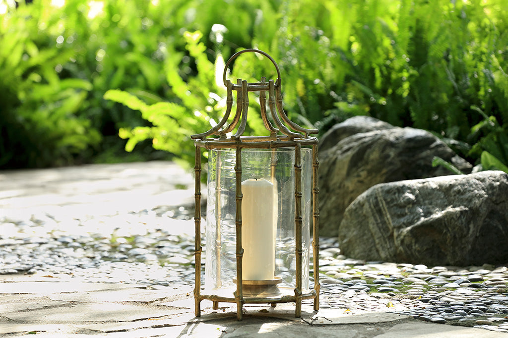 Outdoor metal lantern with bamboo details staged on rocks