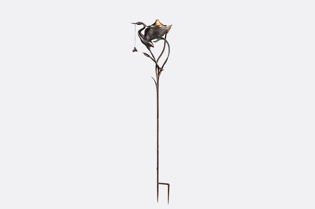 open winged crane with cattails holding oil torch reservoir, staked oil