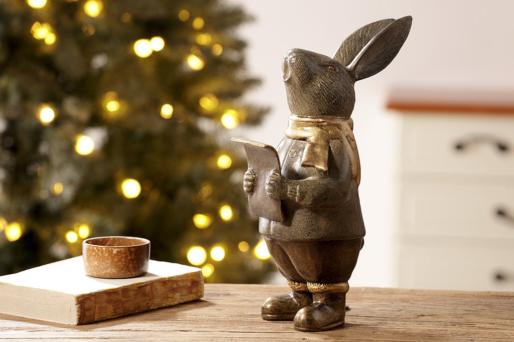 Caroling bunny sculpture holding a music sheer and wearing a hold scarf