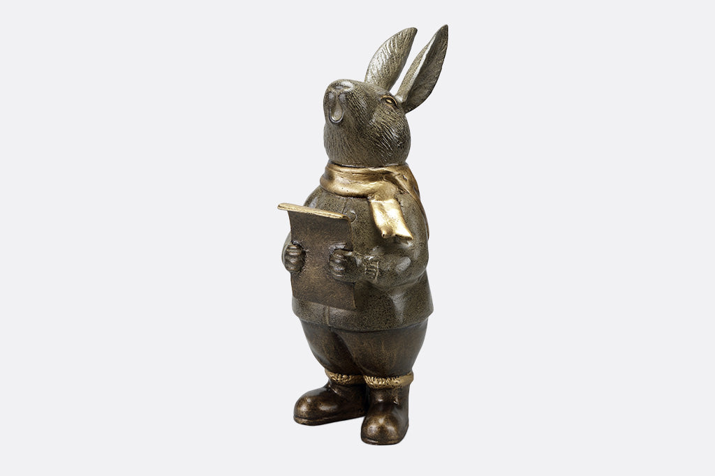 Caroling bunny sculpture holding a music sheer and wearing a hold scarf front view