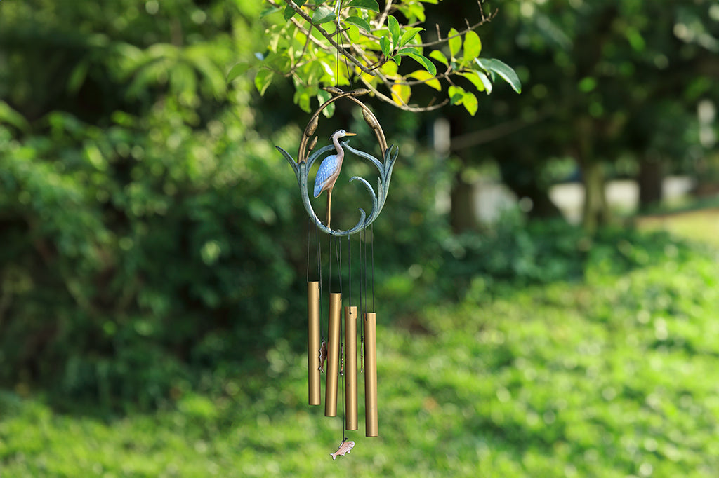 A blue heron is encircled by cattails in a cast metal wind chime, 4 chime tubes and pendant fish move in the wind