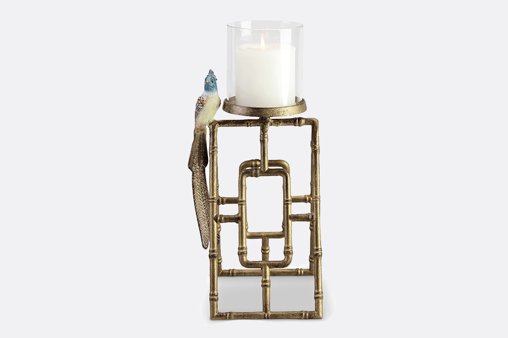 Short cast metal candleholder with blue flycatcher perched on side of glass hurricane candleholder vessel