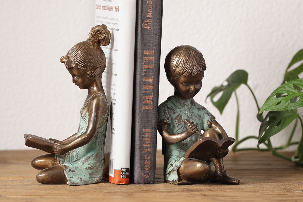 Brass bookends of a girl reading a book and a boy writing in a notebook