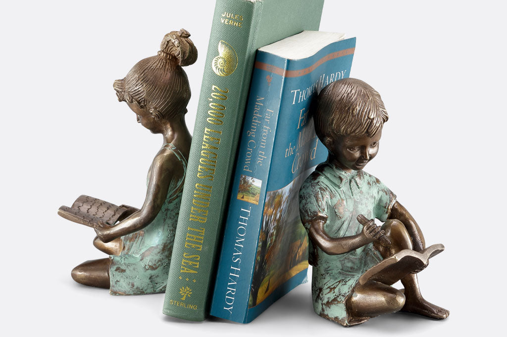 Brass bookends of a girl reading a book and a boy writing in a notebook