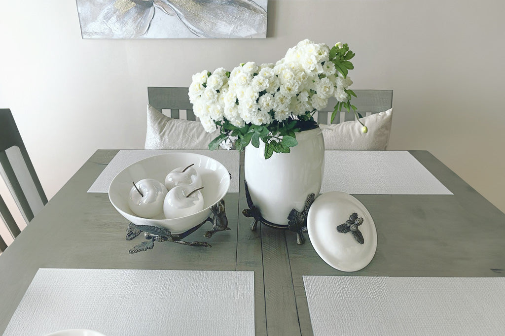 White ceramic serving bowl is supported by a bear climbing on decorative pine branches - shown on dining table