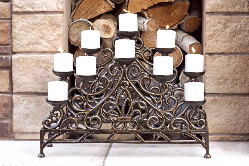Stylized Fleur de Lys Fireplace Candelabra Bronze in front of wood nook, holding 10 lit candles
#color_bronze