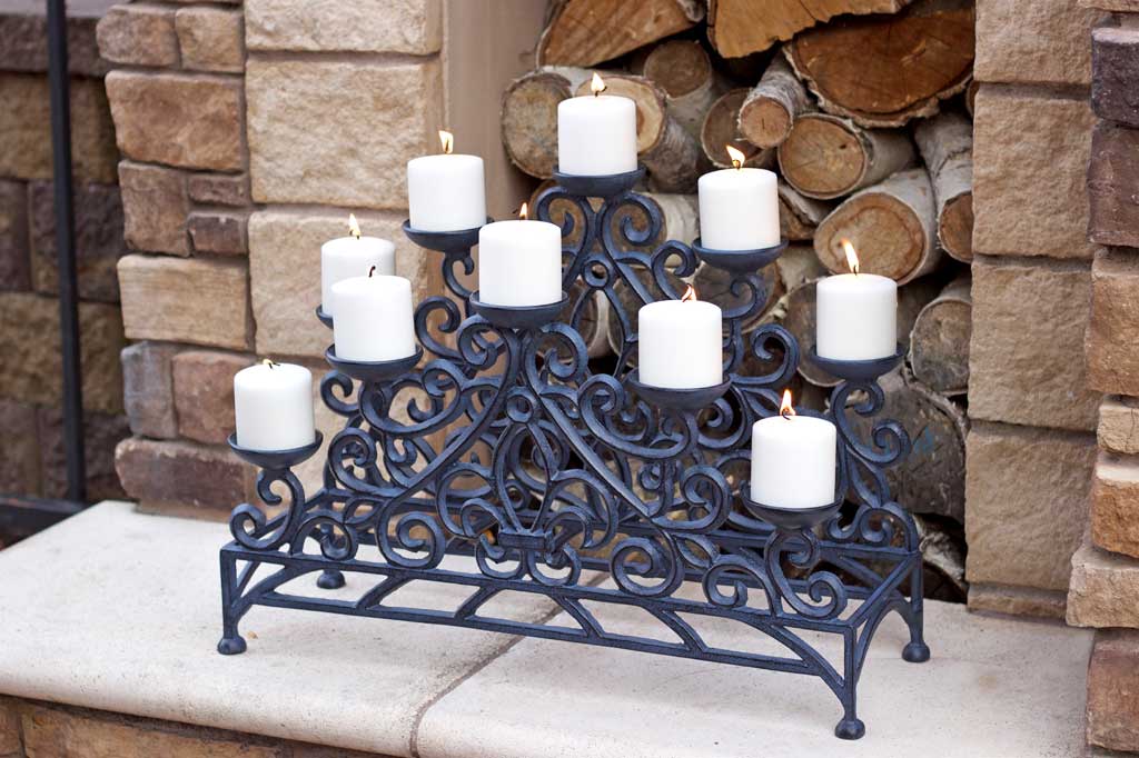 Stylized Fleur de Lys Fireplace Candelabra Zinc on a hearth with 10 lit pillar candles
#color_zinc