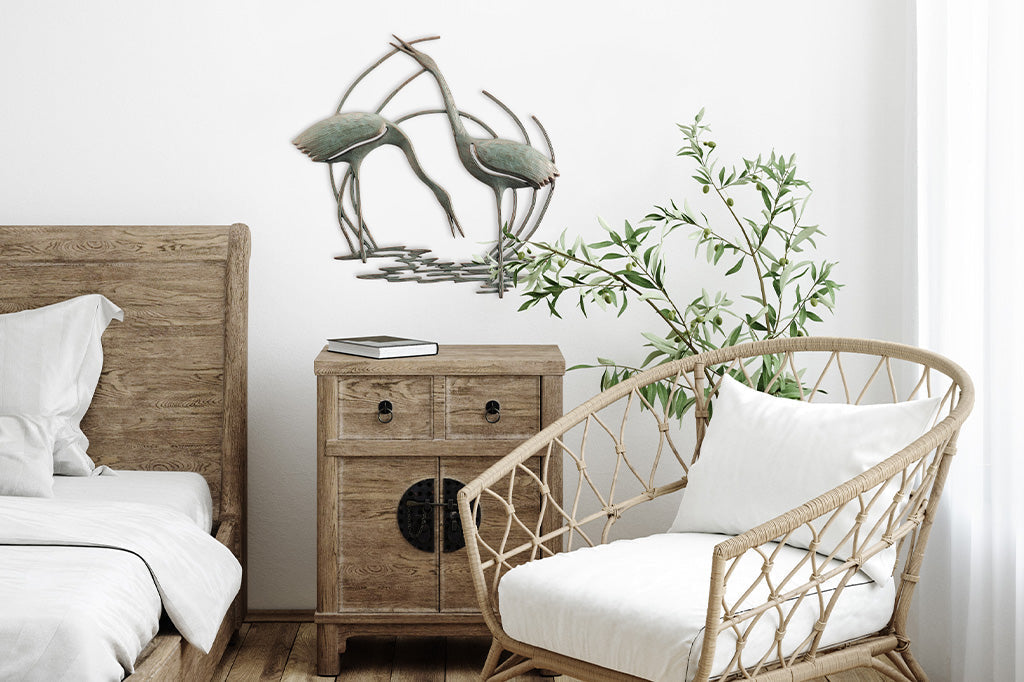 Wall plaque of two cranes standing in reeds and water - placed above nighttand in bedroom scene