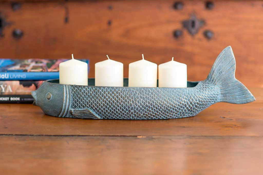 Fish Candleholder with 4 pillar candles, lit, on wood table