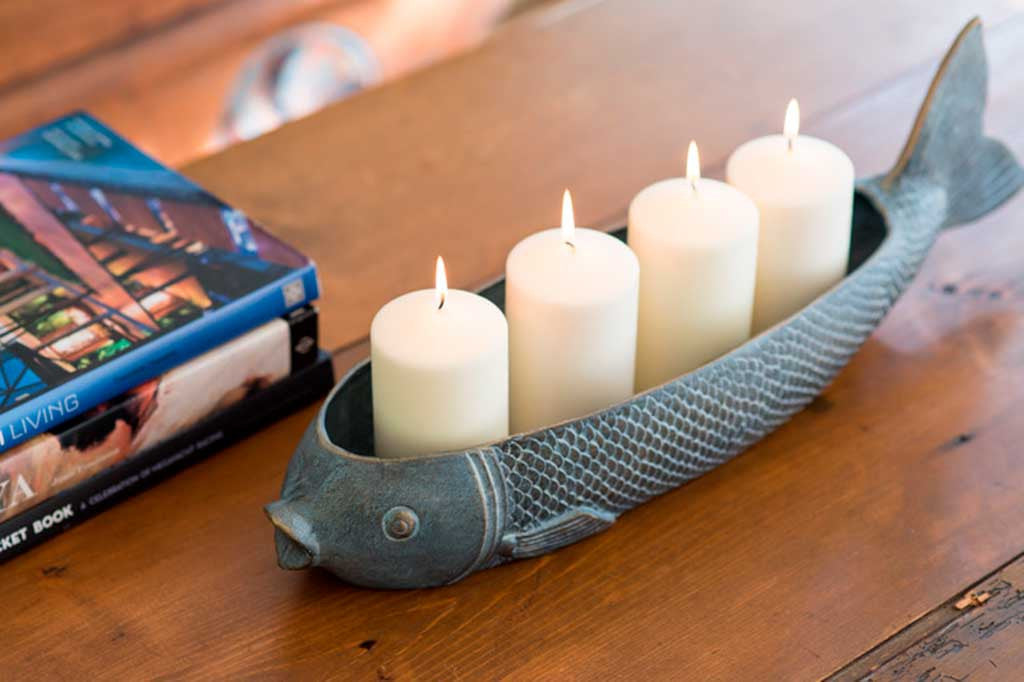 Fish Candleholder with 4 pillar candles, lit, on wood table