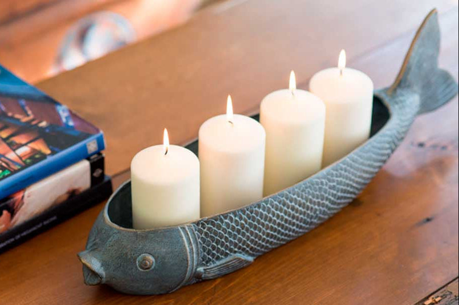 Fish Candleholder with 4 pillar candles, lit, on wood table