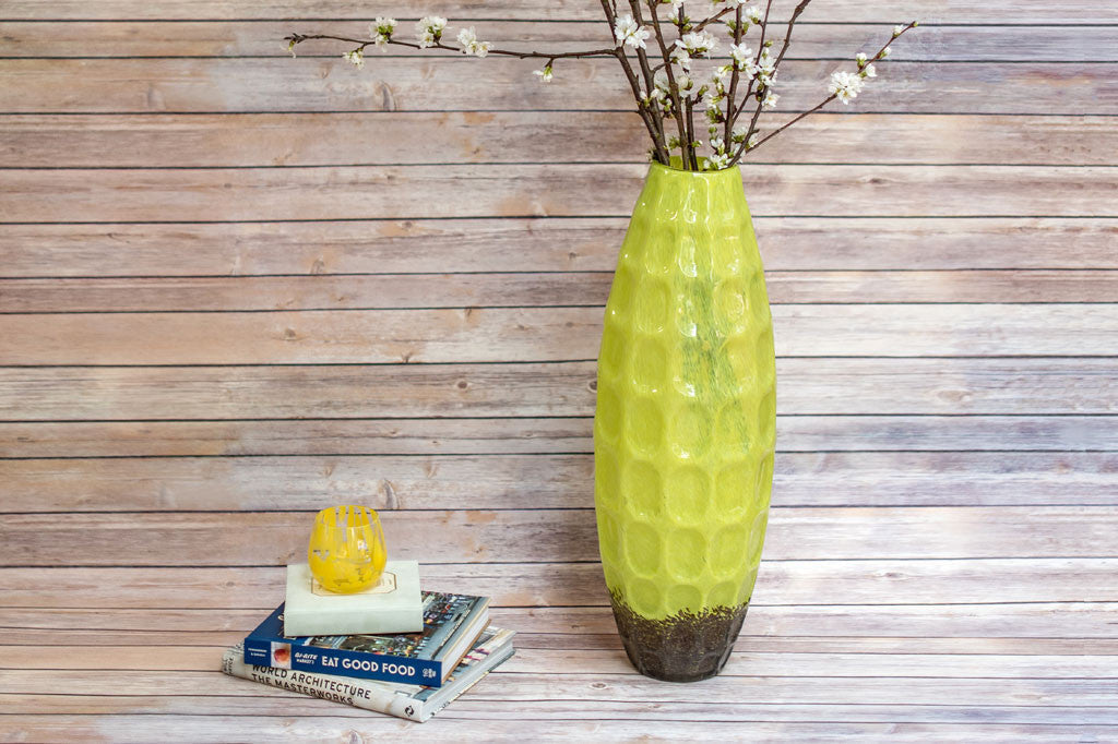 Alto Chartreuse Vase shown on wood bench; holding cherry blossoms and books stacked nearby