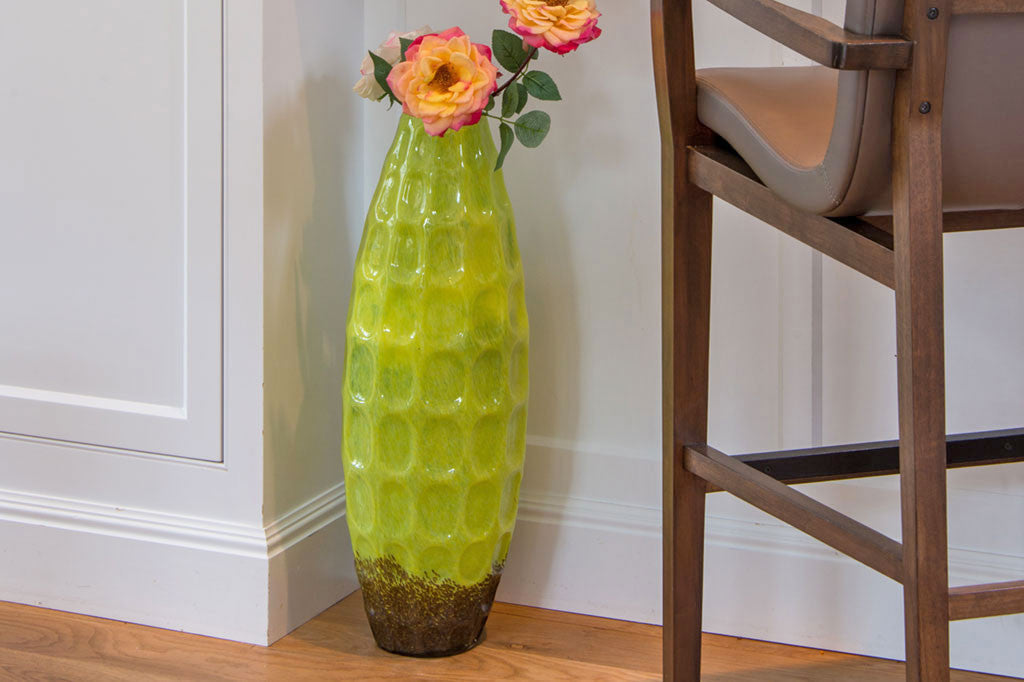 glass vase shown in corner of room holding wild roses