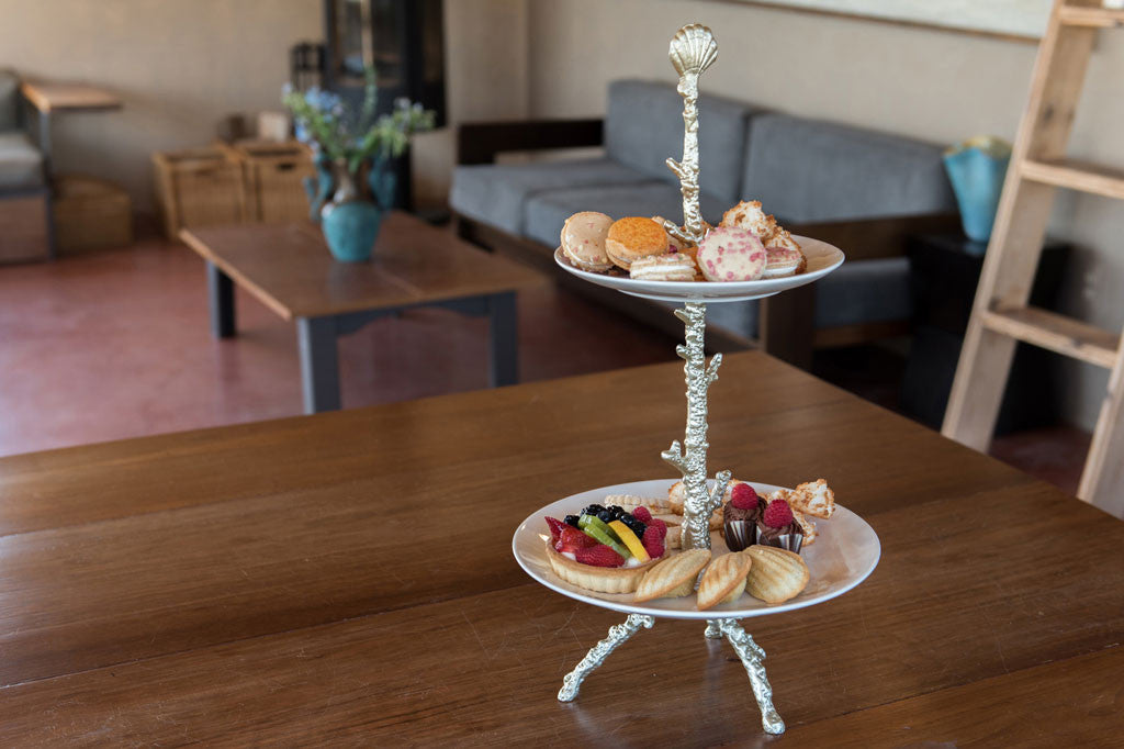 Pacifica Plate Stand shown on wood table in coastal home - features silver finish coral motif