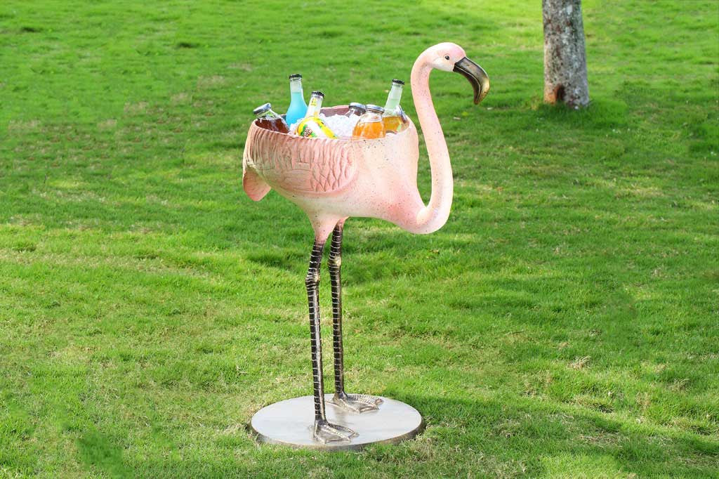 Flamingo shaped beverage tub holding sodas and ice on a lawn