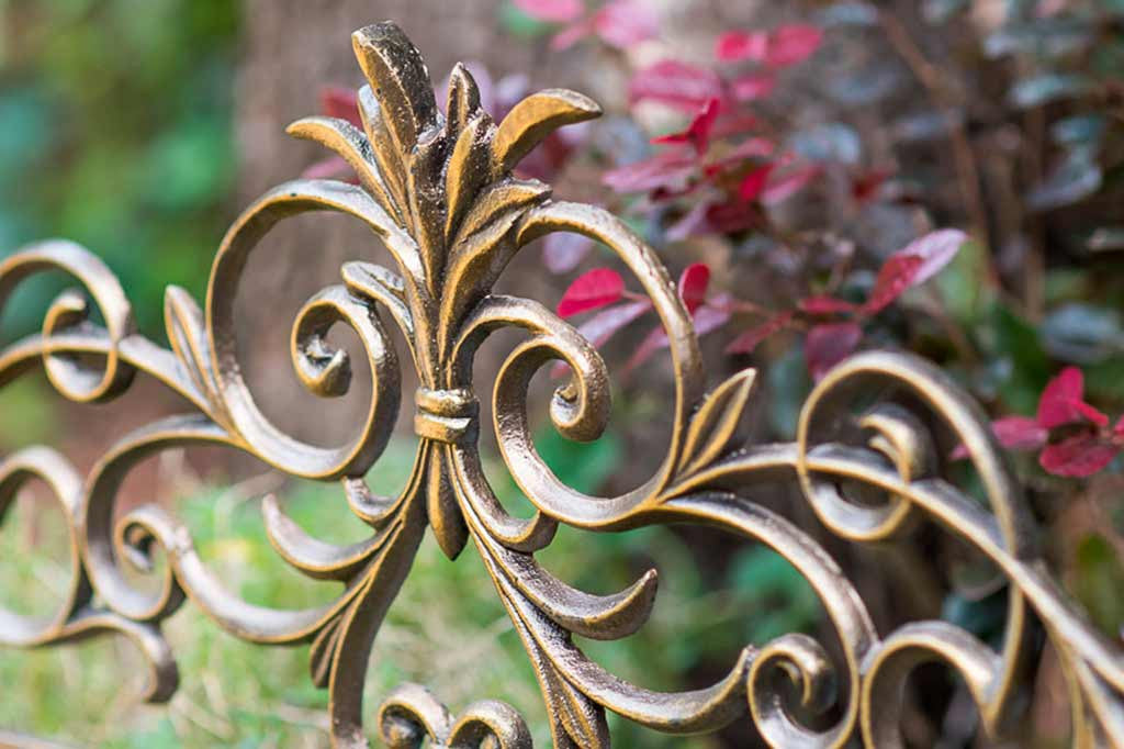 Scrollwork and sheaf of wheat design shown on the Alloro Garden Edging in a garden