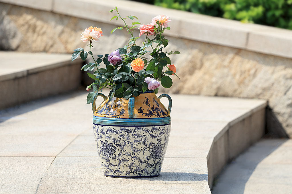 hand painted and thrown ceramic pot with mediterranean prints done in vivid yellow-orange, light and dark blue with floral print on white