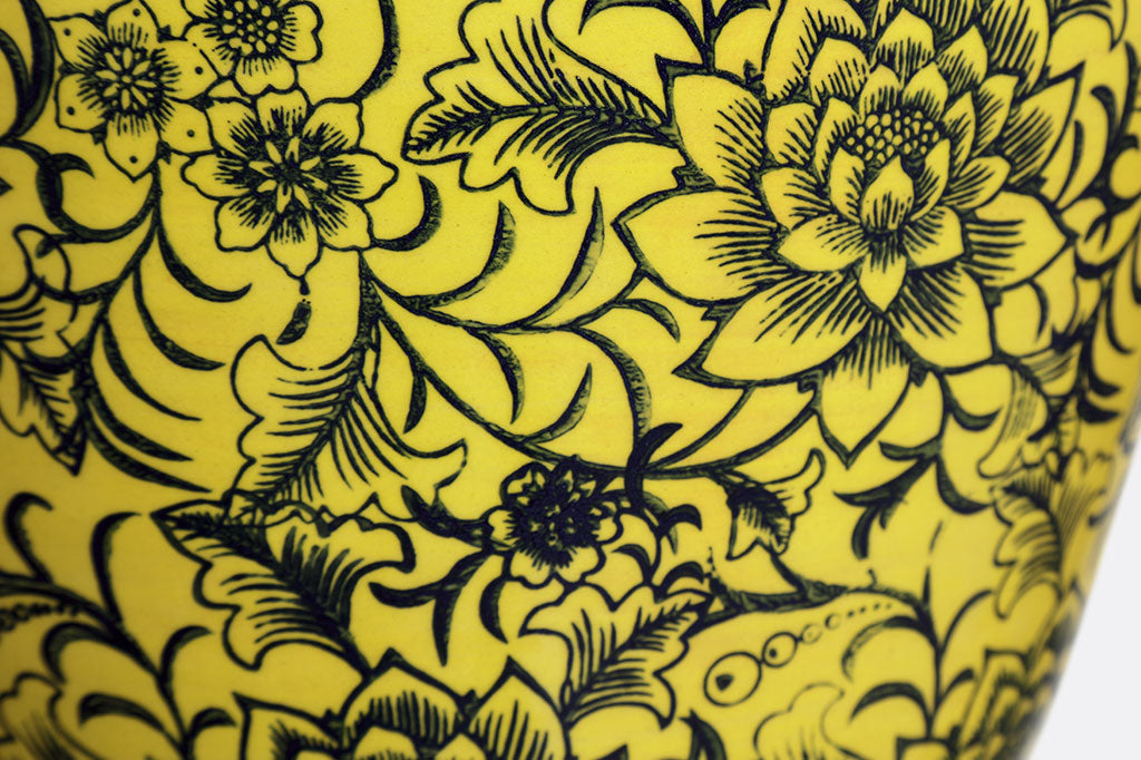 close up of stamped floral and vine motif over yellow ceramic glaze