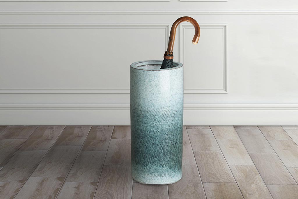 umbrella stand shown on wood floor in home, holding a wood handled umbrella