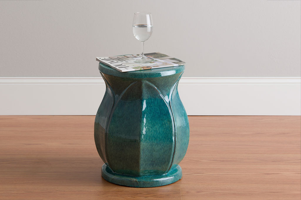 ceramic glazed teal stool shown with wine glass and magazine in a room