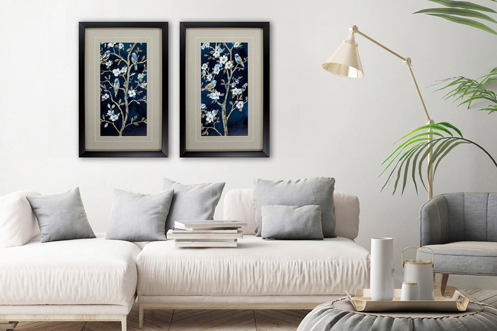 two paintings in wooden frames set behind living room couch