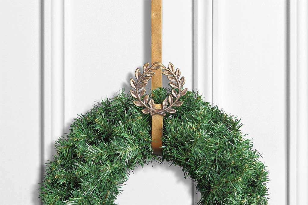 laurel branch motif wreath hanger shown with evergreen wreath on white door