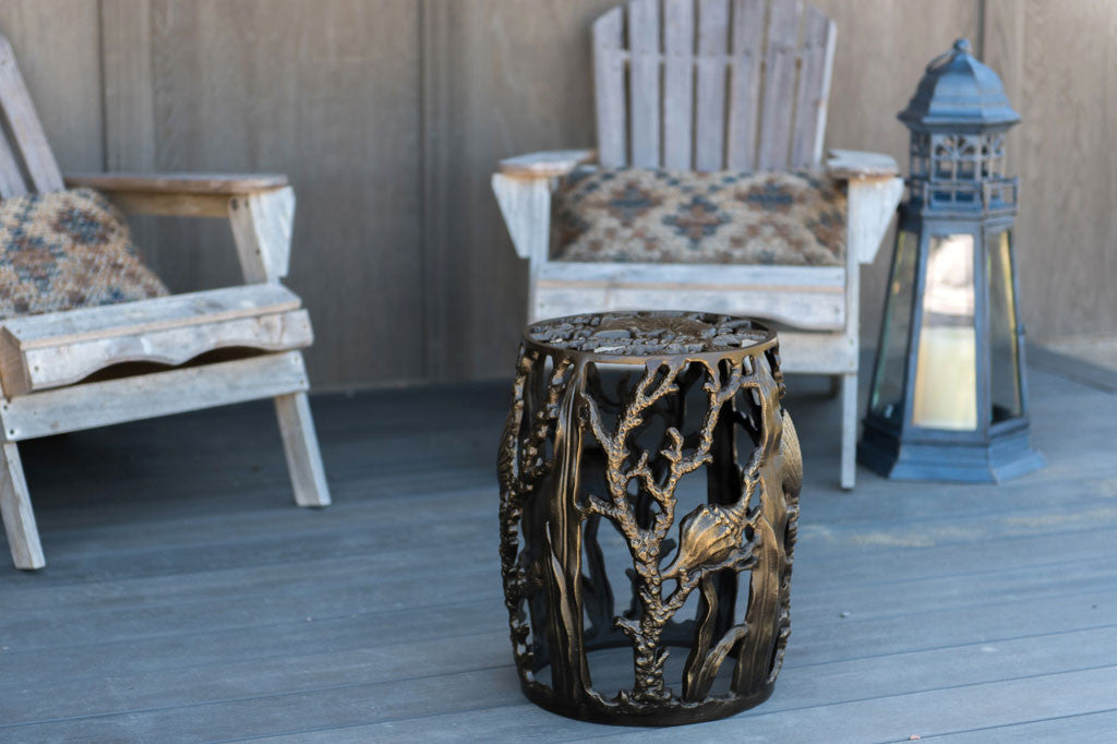 Bronze finish Under The Sea Garden Stool shown on deck of beach house with wood chairs in background
#color_bronze
