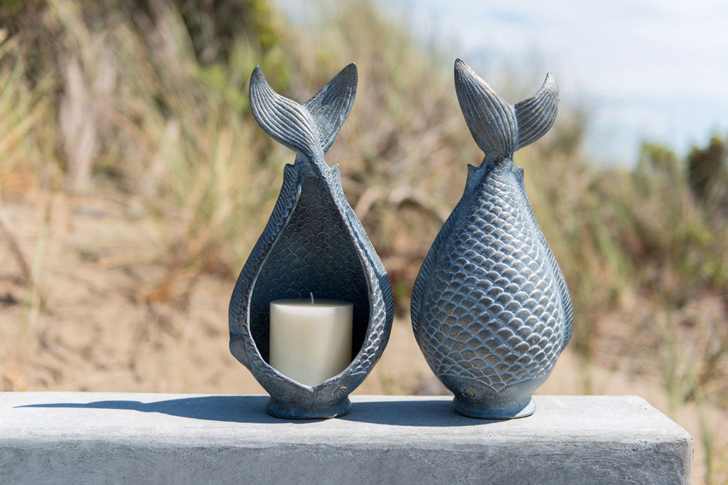 Diving Fish Candleholders shown by beach grass on concrete wall; one shows a candle, the other shows sculpted fish scales