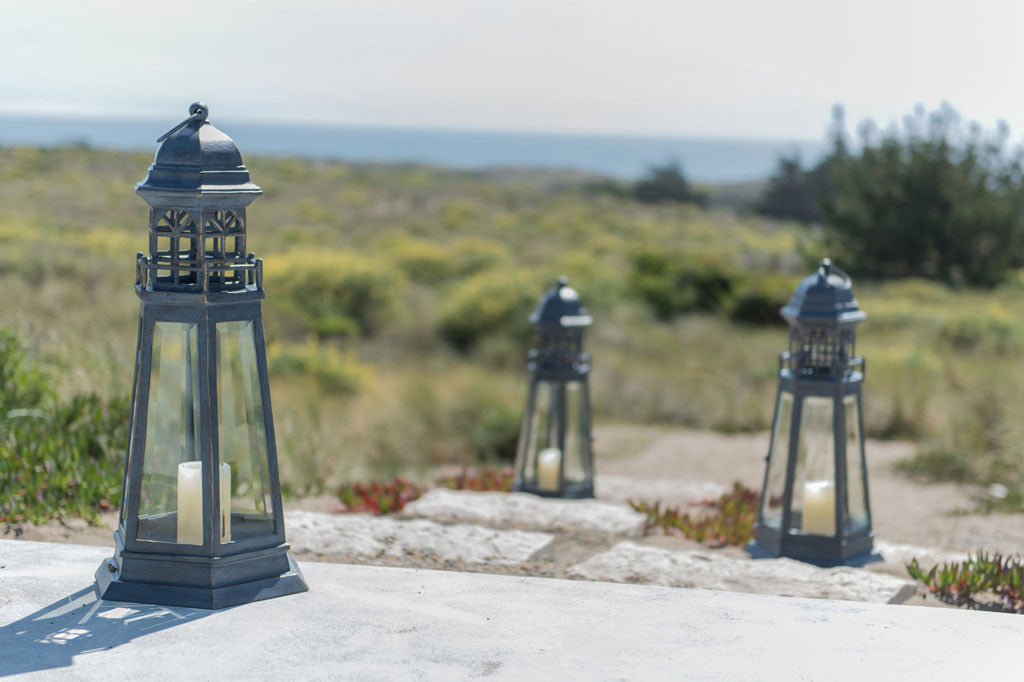 Lighthouse Lantern shown on the steps leading to a beach dune with sea grass and ocean in background.