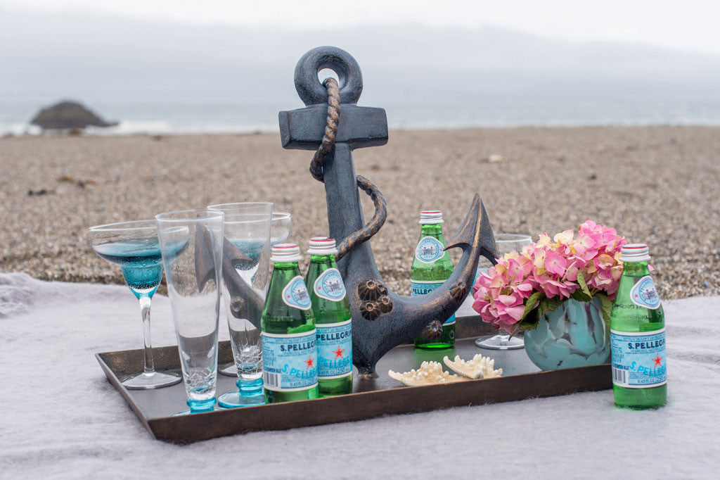 Anchor Tray shows blue-zinc finish anchor complete with rope and barnacle accents- pictured on beach blanket on overcast day serving picnic drinks