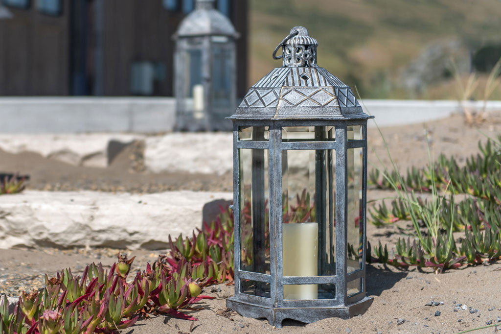 Sea Ranch Lantern shown on sand near a beach house next to iceplant