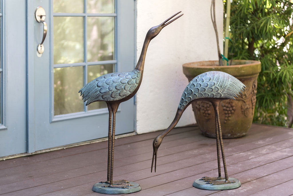 Verdi Crane Pair cast metal garden sculptures set on outdoor porch