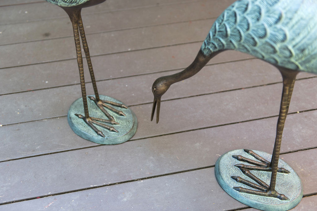 Verdi Crane Pair cast metal garden sculptures set on outdoor porch